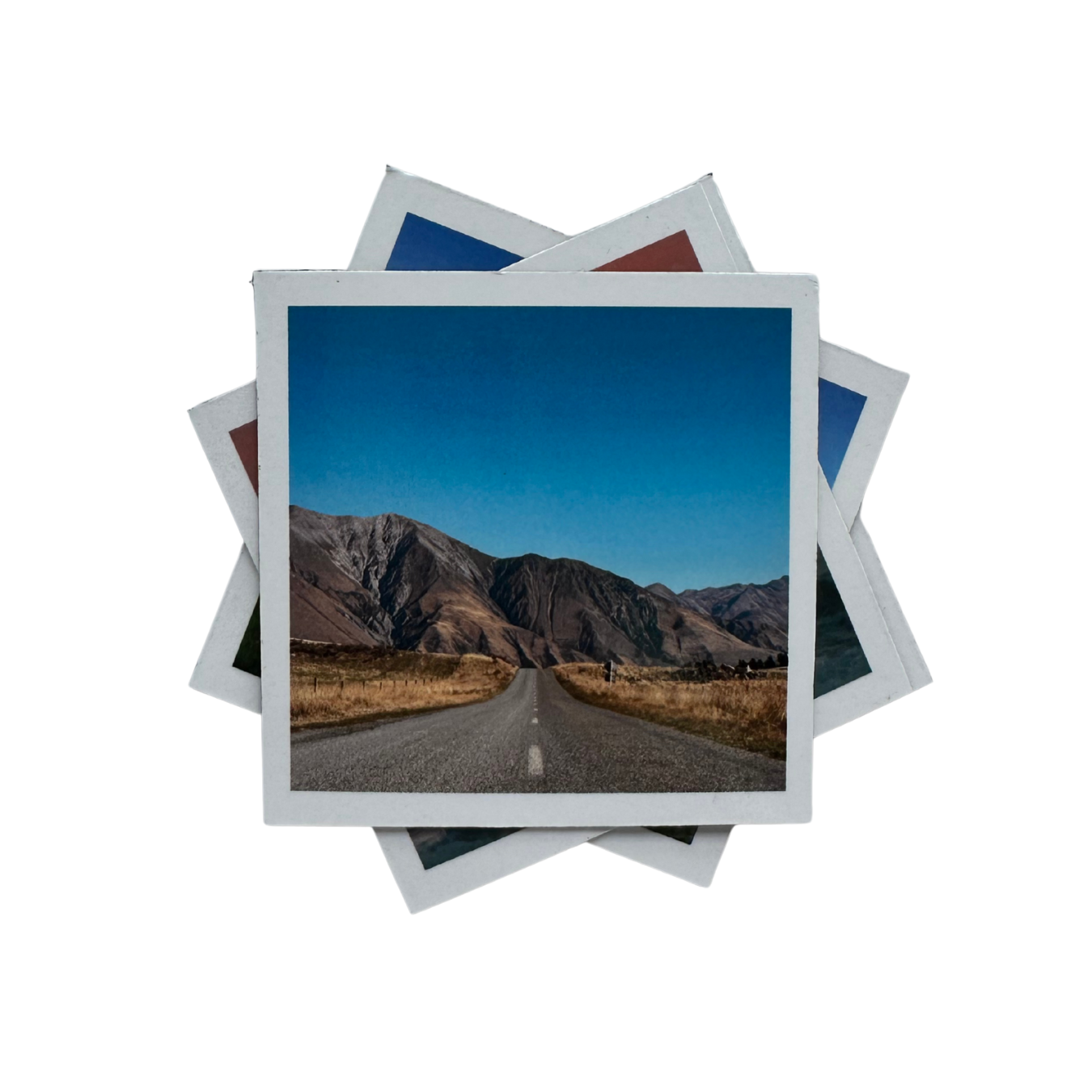 Stack of magnetic photo prints with a scenic road and mountains.