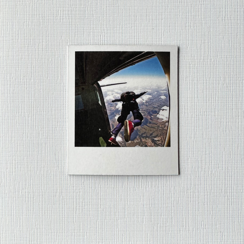 Framed photo of a person skydiving with a view of the Earth from an airplane window. 6 pack polaroid custom photo magnets. 