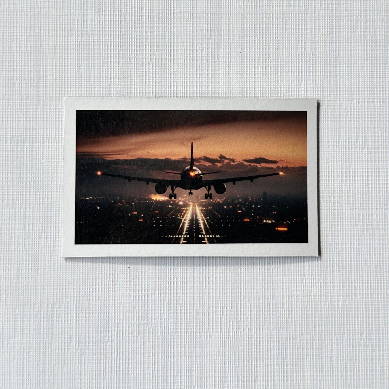 Framed photograph of an airplane landing at dusk over a cityscape. Rectangle photo magnet custom 8 pack. 