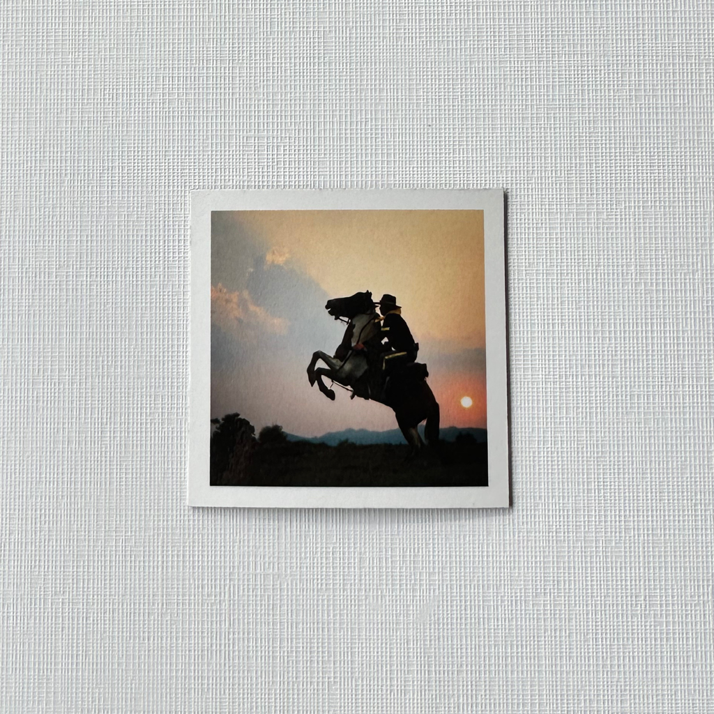 Framed artwork of a silhouette of a person on a horse against a sunset sky, mounted on a textured wall. square 8 pack custom photo magnets.